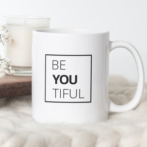 Könnte beinhalten: Weiße Keramik-Kaffeetasse mit einem schwarzen quadratischen Design, auf dem "BE YOU TIFUL" steht.