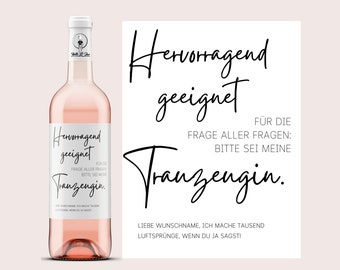 May include: A pink wine bottle with a white label that says "Hervorragend geeignet" and "Tranzengin." The label also includes the text "Für die Frage aller Fragen: Bitte sei meine Tranzengin."