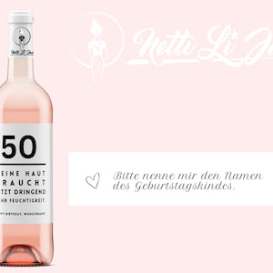May include: A pink wine bottle with a white label that says "50" and "DEINE HAUT BRAUCHT JETZT DRINGEND MEHR FEUCHTIGKEIT. HAPPY BIRTHDAY, WUNSCHNAME". The bottle is on a pink background with the text "Netti Li Jae" in white.