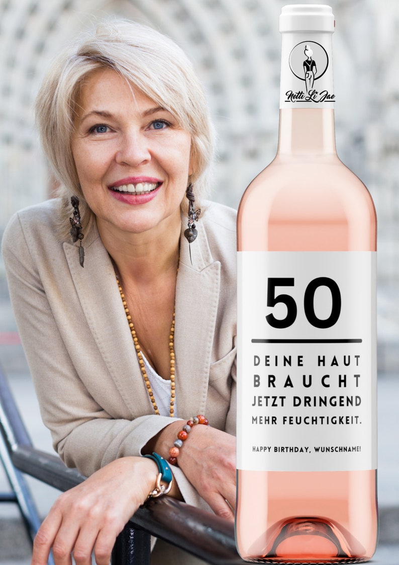 May include: A pink wine bottle with a white label that says "50" in black text. The label also says "Deine Haut Braucht Jetzt Dringend Mehr Feuchtigkeit." and "Happy Birthday, Wunschname!" in black text. The bottle is topped with a cork and has a white label with a black silhouette of a woman and the text "Netti Li Jae".