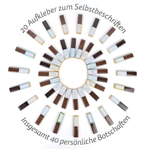 May include: A circle of 40 small chocolate bars with colorful labels. The labels have blank spaces for writing personalized messages. The text around the circle reads "20 Aufkleber zum Selbstbeschriften" and "Insgesamt 40 pers&ouml;nliche Botschaften".