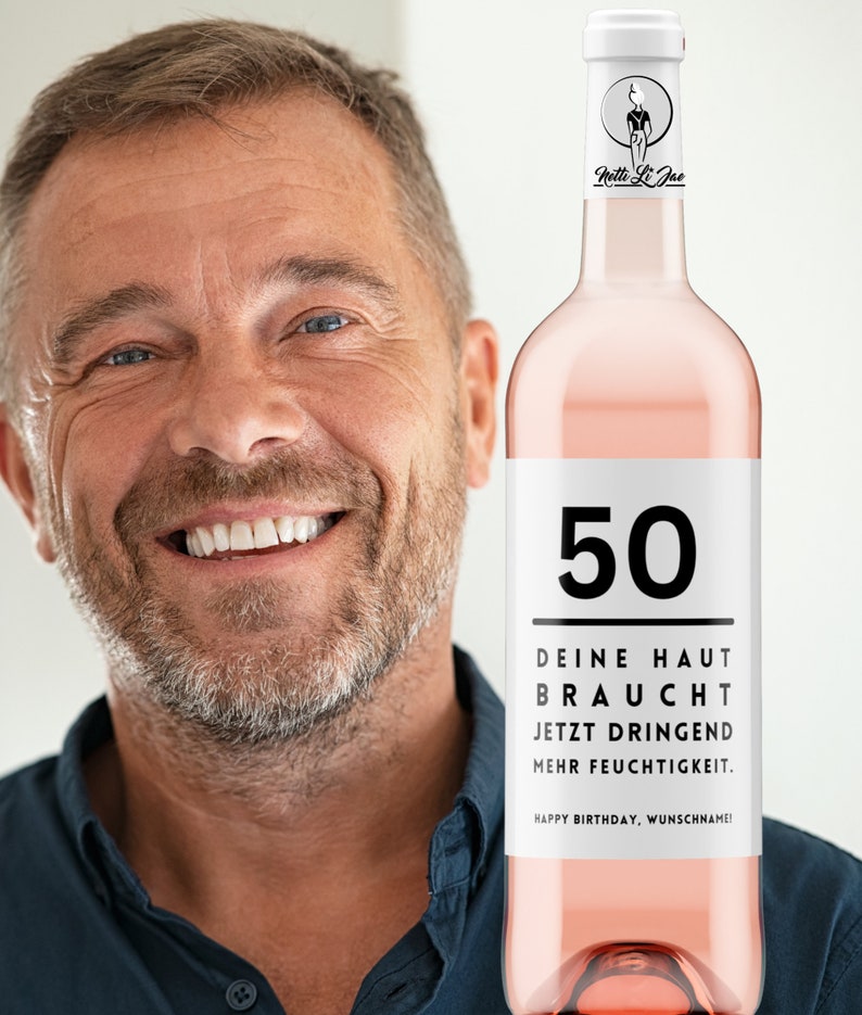 May include: A pink wine bottle with a white label that says "50" and "DEINE HAUT BRAUCHT JETZT DRINGEND MEHR FEUCHTIGKEIT. HAPPY BIRTHDAY, WUNSCHNAME!"