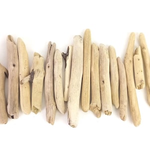 May include: A collection of light tan driftwood pieces arranged in a horizontal row. Each piece of wood features a smooth, weathered texture with natural variations in shape, thickness, and length, showcasing organic patterns and light brown tones.