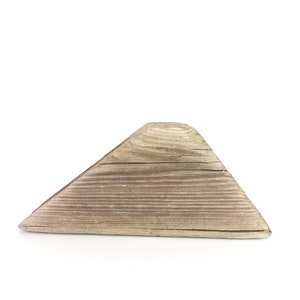 Puede incluir: Una pieza triangular de madera desgastada con un acabado de veta de madera natural.