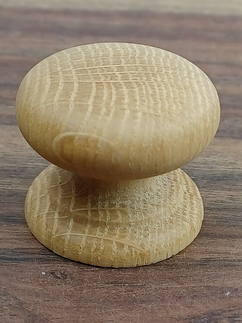 May include: A light brown wooden knob with a rounded top and a slightly smaller base. The knob has a smooth, polished finish and a subtle grain pattern.