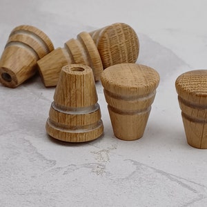 May include: Five wooden knobs with a light brown finish and white accents. The knobs have a variety of shapes and sizes.
