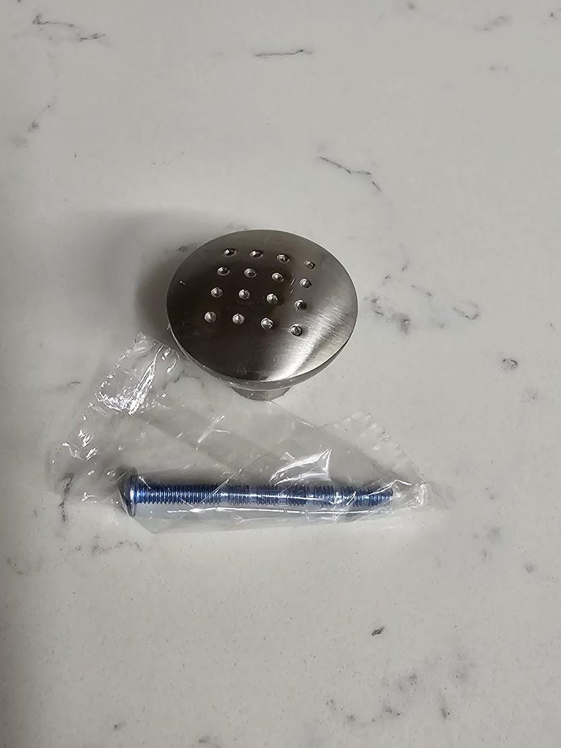 Puede incluir: Un pomo de armario plateado con un dise&ntilde;o redondo y plano y un patr&oacute;n de peque&ntilde;os agujeros. Viene con un tornillo plateado.