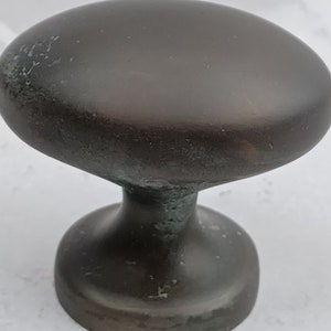 May include: A dark brown oval cabinet knob with a round base.
