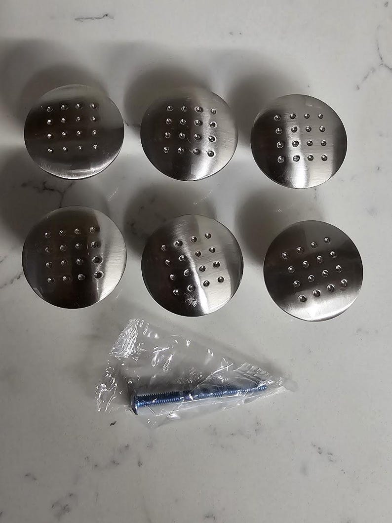 Puede incluir: Seis pomos de armario plateados con un patr&oacute;n de puntos y un tornillo plateado en una bolsa de pl&aacute;stico.