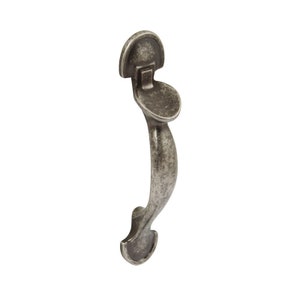 May include: A silver-toned door handle with a curved design and a decorative top plate. The handle has a distressed finish.