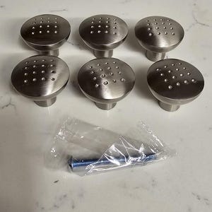Puede incluir: Seis pomos de armario plateados con un patr&oacute;n de puntos. Los pomos son redondos y tienen un borde elevado. Vienen con un solo tornillo para la instalaci&oacute;n.