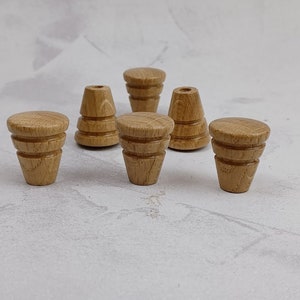 May include: Six wooden knobs with a cone shape and a fluted design. The knobs are a light brown colour.