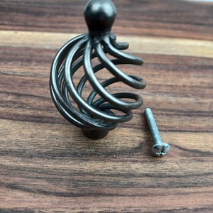 May include: Black metal cabinet knob with a spiral design and a matching screw.