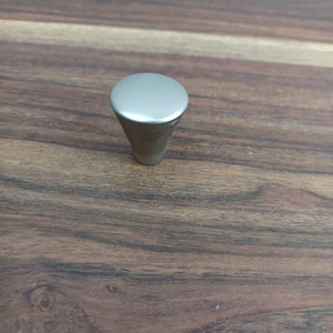 May include: A silver-toned, cone-shaped cabinet knob with a rounded top.