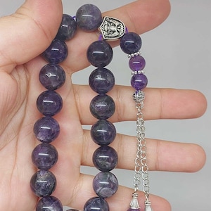 May include: A purple amethyst prayer bead mala with a silver charm and tassel. The beads are round and have a natural, slightly uneven texture.