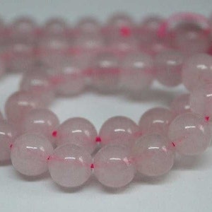 May include: A strand of pale pink oval-shaped beads. The beads are translucent and have a slight shimmer.
