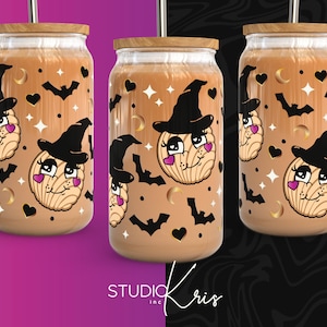 Puede incluir: Tres vasos de vidrio marrón con tapas y pajitas. Cada vaso presenta un diseño de temática de Halloween con un sombrero de bruja y un pastel de concha. El diseño es en negro, blanco y rosa.