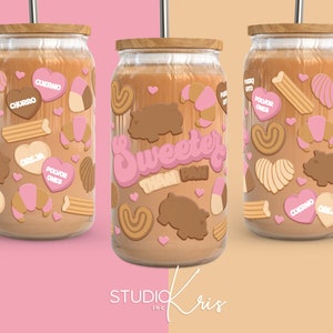 Può includere: Tre barattoli di vetro con coperchi marroni e liquido marrone all'interno. I barattoli sono decorati con immagini di cartoni animati rosa e marroni di cuori, pasticcini e la parola "Sweeter's".