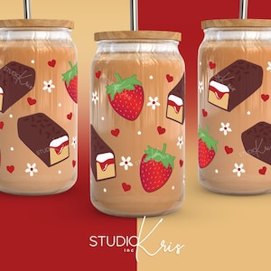 May include: Three glass tumblers with lids and straws, featuring a pattern of chocolate-covered strawberries and chocolate bars with strawberry filling. The tumblers are filled with a light brown liquid.