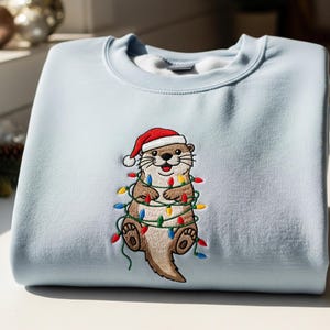 Christmas Otter Embroidered Sweatshirt – Cute Holiday Animal Crewneck – Otter Wrapped in Lights – Funny Santa Sweatshirt Gift for Her