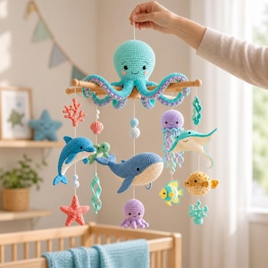 Könnte beinhalten: Ein hängendes Mobile mit gehäkelten Meerestieren, darunter ein großer türkisfarbener Oktopus an der Spitze, ein blauer Wal, ein Delfin, ein Rochen, eine Qualle, ein Kugelfisch, ein gelber Fisch, ein Seestern, eine Koralle und eine kleine grüne Schildkröte.