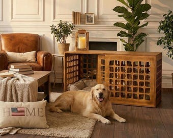 May include: A golden retriever dog lies on a beige rug in front of a wooden dog crate with a sliding door. The crate is next to a beige dog bed. A pillow with the word "HOME" and an American flag is on the rug.