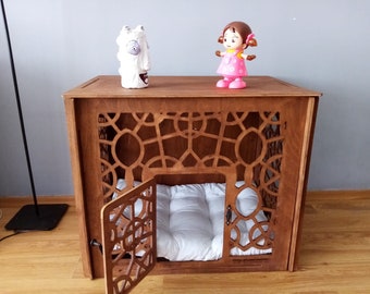 May include: A brown wooden pet crate with an intricate geometric cutout pattern on the front and side panels. The crate features a hinged door that is currently open, revealing a plush white tufted cushion inside the enclosure.