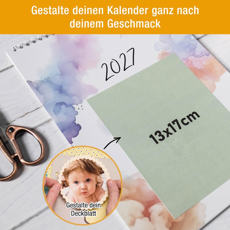 May include: A 2027 wall calendar with watercolor accents and a sage green rectangular overlay labeled 13x17cm. A circular inset shows a scalloped-edge photo of a baby with the German text Gestalte dein Deckblatt. Copper scissors are visible.