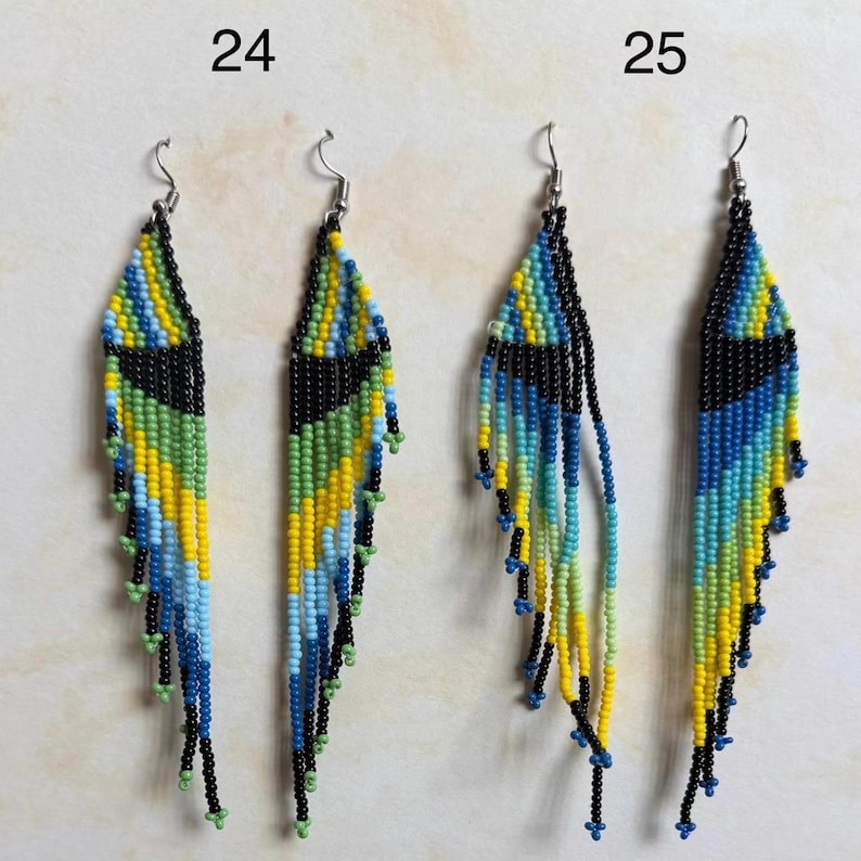 May include: Handmade beaded earrings in a feather design. The earrings feature a black top section with a geometric pattern in yellow, green, and blue. The fringe is made of black beads with accents of yellow, green, and blue.