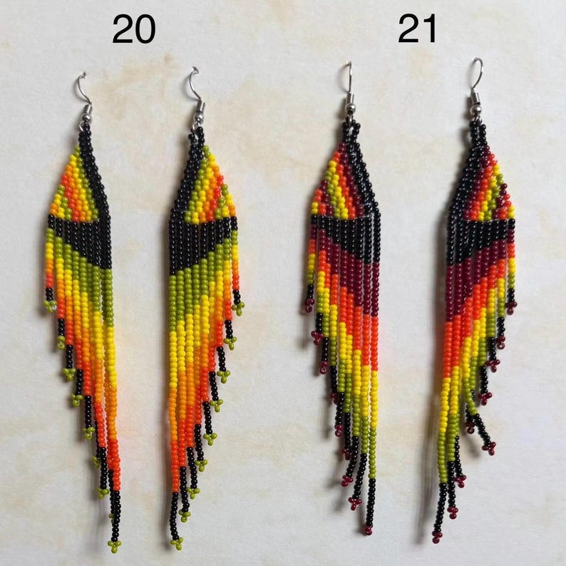 May include: Two pairs of beaded earrings. One pair features a color gradient of yellow, orange, and black beads. The other pair has a color gradient of red, orange, and black beads. Both pairs have silver-colored ear wires and small beaded tassels.
