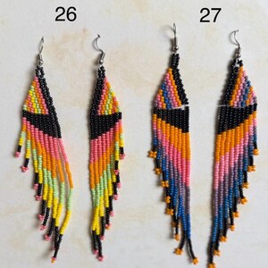 May include: Two pairs of beaded earrings with a geometric design. Each earring features a black triangle and is adorned with pink, orange, yellow, and green beads. The earrings are labeled with the numbers 26 and 27.