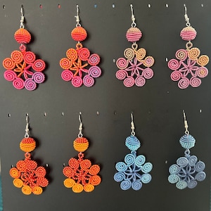Könnte beinhalten: Ein Set mit 10 bunten gehäkelten Ohrringen. Jeder Ohrring hat ein blumenförmiges Design mit einer einzelnen Perle oben. Die Ohrringe sind in verschiedenen Farben erhältlich, darunter Pink, Blau, Orange und Rot.
