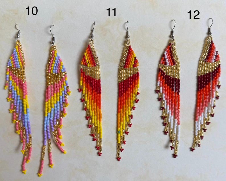 May include: Three pairs of beaded dangle earrings. The earrings feature a variety of colors, including pink, yellow, orange, red, and gold. Each earring has a gold-colored top and a fringe of beads. The earrings are designed for pierced ears.