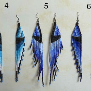 May include: A collection of six beaded earrings in shades of blue, black, and white. The earrings feature a geometric design with a fringe of beads at the bottom. Each earring has a silver-colored hook.