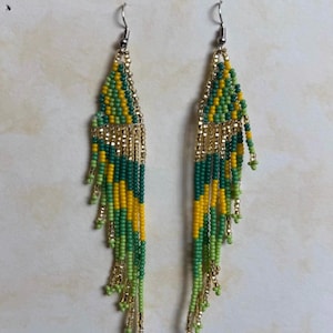 May include: A pair of beaded earrings with a gold-colored top and fringe. The earrings feature a pattern of green, yellow, and dark green beads. The number "32" is in the top left corner.