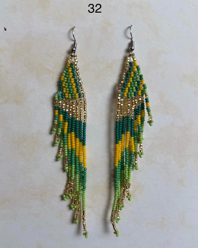 May include: A pair of beaded earrings with a gold-colored top and fringe. The earrings feature a pattern of green, yellow, and dark green beads. The number "32" is in the top left corner.