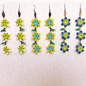 Brincos Chaquira Huichol com pingentes de flores e miçangas, com três flores.