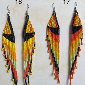 May include: Two pairs of beaded earrings. Each earring features a triangular top in black, yellow, and orange, with long beaded fringe in matching colors. The earrings are labeled with the numbers 16 and 17.