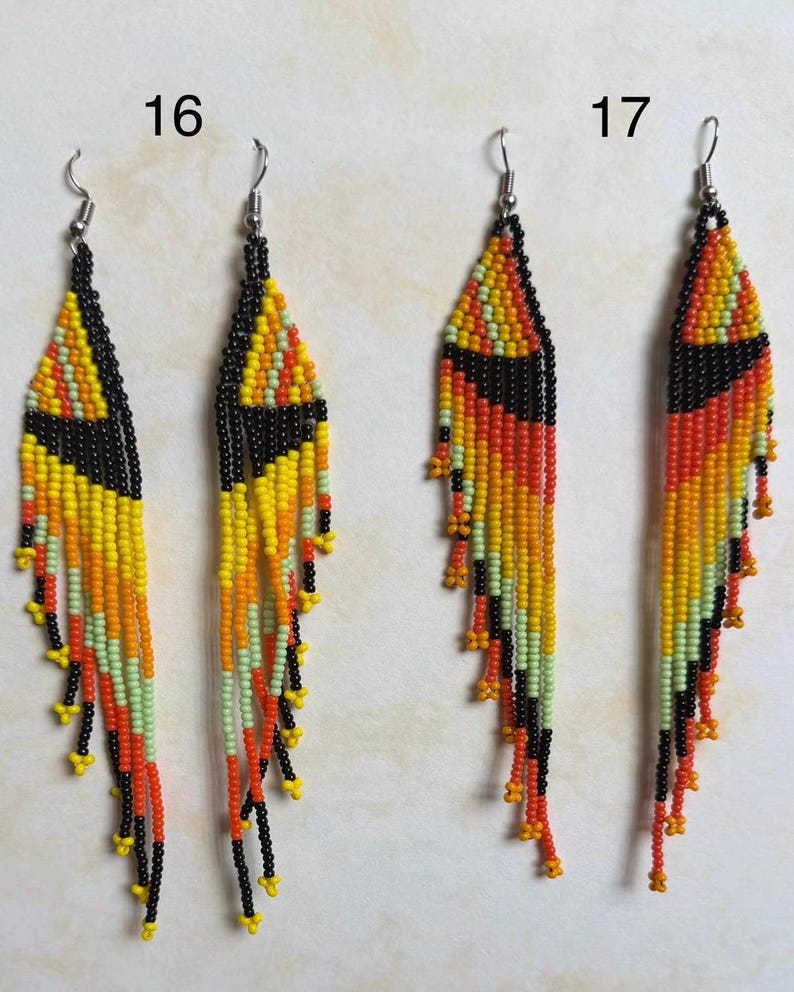 May include: Two pairs of beaded earrings. Each earring features a triangular top in black, yellow, and orange, with long beaded fringe in matching colors. The earrings are labeled with the numbers 16 and 17.