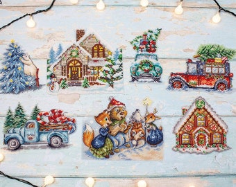 May include: A set of eight cross-stitch patterns featuring winter holiday scenes. The patterns include a gingerbread house, a truck with a candy cane, a house with a snowman, a truck with a Christmas tree, a group of animals, and a car with presents.