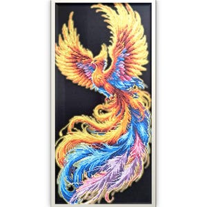 May include: A framed artwork featuring a vibrant phoenix design. The bird is depicted with outstretched wings and a flowing tail, showcasing a palette of gold, orange, blue, and purple hues against a black background. The artwork is framed in a white border.