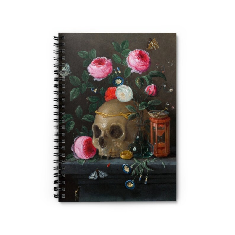 May include: Spiral-bound notebook featuring a still life painting with a skull, roses, and butterflies. The artwork has a dark background and a vintage aesthetic. The skull is adorned with a gold crown, and the roses are pink and red.