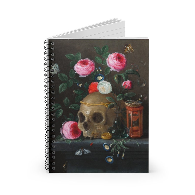May include: Spiral-bound notebook featuring a still-life painting with a skull, roses, and butterflies. The artwork has a dark background with a skull adorned with a gold crown, surrounded by pink and white roses, and a small hourglass.