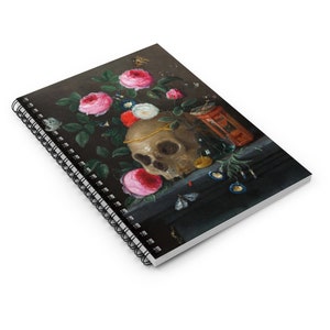 May include: Spiral-bound notebook featuring a still life painting with a skull, roses, and butterflies. The artwork has a dark background with a skull adorned with a gold chain, surrounded by pink, red, and white roses. A small hourglass and other objects are also present.