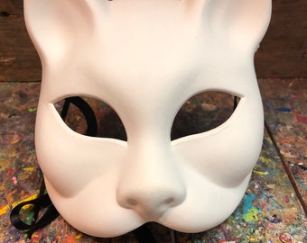 May include: A white cat mask with black eye holes and a black ribbon tie. The mask is made of a smooth, matte material and has a realistic cat face design.