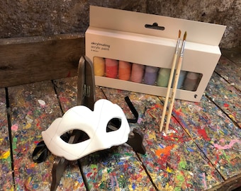 Può includere: Una maschera di plastica bianca con un design semplice, due pennelli e una scatola di 8 tubetti di vernice acrilica in vari colori pastello. I tubetti di vernice sono etichettati "akrylmåling acrylic paint".