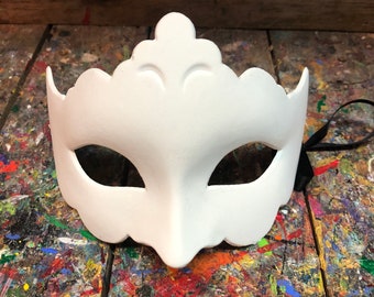 May include: A white masquerade mask with a decorative, scalloped edge and a raised design. The mask has two eye holes and a black ribbon attached.