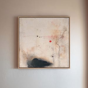 May include: Abstract art piece in a natural wood frame. The artwork features a cream-colored background with black, red, and brown accents. A black cloud-like shape is at the bottom, with a red dot and black dots scattered across the canvas.