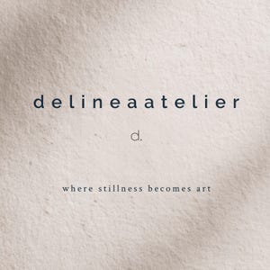 May include: A minimalist design featuring the text "delineaatelier" in a dark blue font, with a smaller "d." beneath it. The phrase "where stillness becomes art" is below, all set against a textured, off-white background.