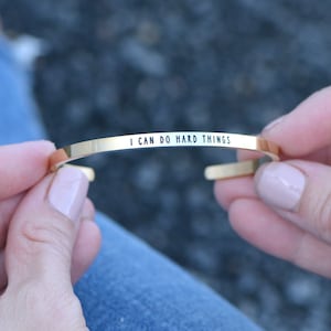 May include: Gold-toned bangle bracelet with the inscription "I can do hard things".